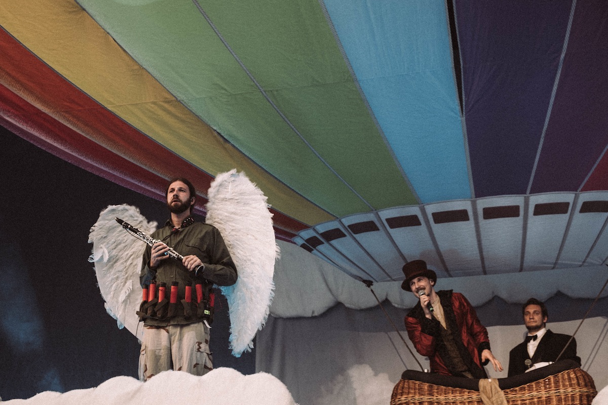 Alligatoah im fragwürdig-seltsamen Selbstmord-Attentäter-Kostüm, als Engel im Himmel unterwegs mit einem Regenbogenballon.