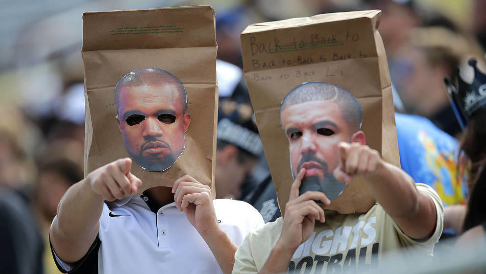 Zwei Rap-Fans tragen Pappmasken von Drake und Kanye West während eines Football-Spiels in Florida.